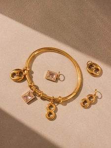 Macro view of gold stainless steel bangle with high-shine zircon charms and mirror finish