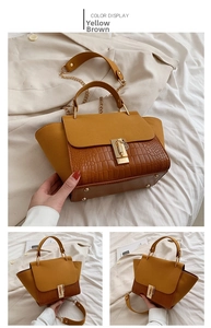 Detail of yellow-brown handbag featuring crocodile pattern leather and gold metal buckle