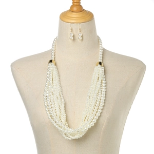 Detail of multi-layered pearl necklace and matching earrings set on a white stand