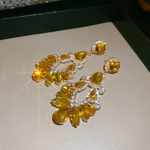 Macro shot of sparkling gold drop earrings with amber crystals and zircon stones