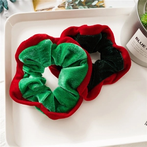 Set of two velvet Christmas scrunchies in festive red and green colors on a white tray