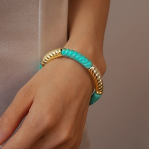 Détail d'un bracelet vintage en acrylique avec maillons filetés dorés et turquoise
