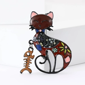 Close-up of enamel cat brooch with fishbone pendant and floral pattern detail