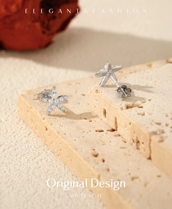 Close-up of S925 sterling silver starfish stud earrings with pearls on textured stone