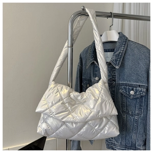 White puffer hobo bag with quilted cloud design hanging over a denim jacket background