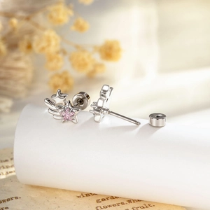 Star-shaped earrings with pink gems and silver wings, shown in a macro professional shot