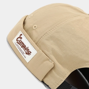 Detail of khaki ripstop brimless cap featuring a camping woven label and metal eyelet