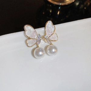 Détail de boucles d'oreilles papillon avec perles et ailes scintillantes serties de zircon