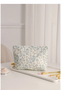 Floral makeup bag on a tray with makeup brushes and elegant cream background