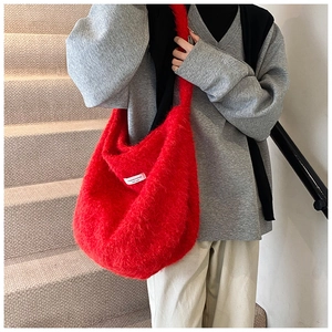 Model wearing red wool shoulder bag with soft plush texture and wide strap on stairs