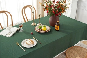 Detail of green washed cotton tablecloth featuring white pom-pom fringe and soft texture