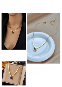 Detail of square blue gem pendant on gold titanium steel necklace with cube accents