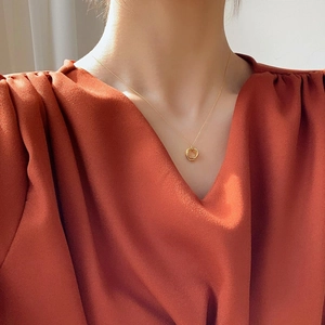 Close-up of minimalist gold double-circle pendant necklace worn by a model