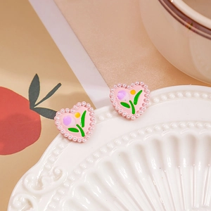 Pink heart-shaped stud earrings with hand-painted tulips and pearls on a ceramic plate