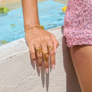 Golden musical note jewelry set with rings and bracelet worn by model poolside