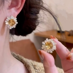Detailed view of sunflower stud earrings with yellow center stone and white zircon petals