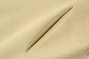 Close-up of beige wool jacket showing high-quality fabric texture and pocket stitching
