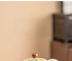 Detail of Ru Kiln ceramic teapot lid with yellow floral patterns and wooden knob handle
