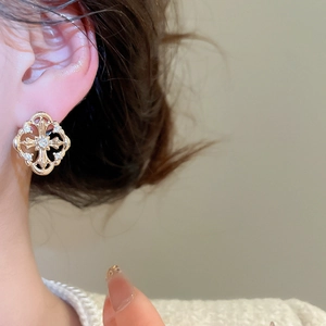 Close-up of vintage golden cross earrings with zircon pavé worn by a female model