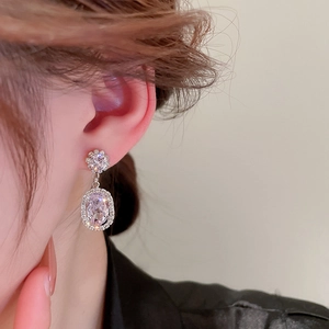 Close-up model shot of sparkling silver flower drop earrings with oval zircons and pearls