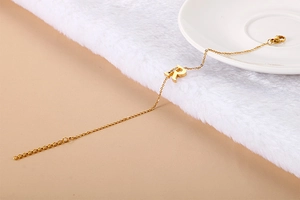 Macro detail of a gold bracelet featuring a diamond-encrusted letter R charm