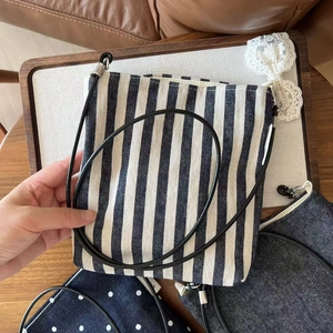 Detailed texture of blue and white striped canvas fabric on a small crossbody bag