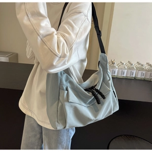 Detail of light blue crossbody tote bag with black adjustable strap on model