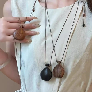 Close-up of hand-carved mini wooden vase pendants with natural grain and adjustable cord