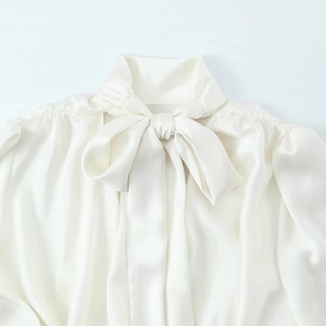 Elegant white satin long sleeve blouse with a bow neckline and pleated shoulder detail
