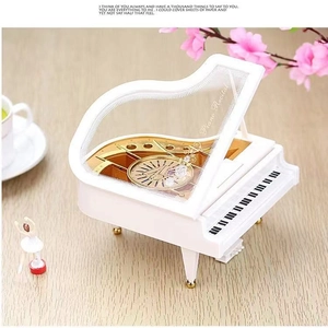 Elegant white grand piano music box with a rotating ballerina dancer on wood background