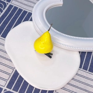 Detail of creative yellow pear hair clip on ceramic tray with glossy resin finish