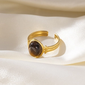 Detailed macro shot of vintage gold-plated ring with oval brown gemstone on silk