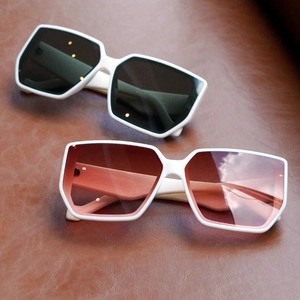 Stylish white oversized square sunglasses with black and gradient lenses on brown leather