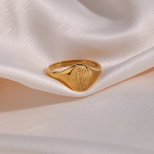 Macro shot of gold signet ring with engraved sunflower on white silk background