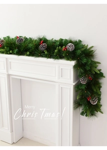 Detail of Christmas garland with pine needles, cones and red berries on a white mantel