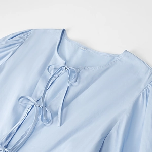 Details von hellblauen Puffärmeln und Rundhalsausschnitt mit Bändern am Kleid