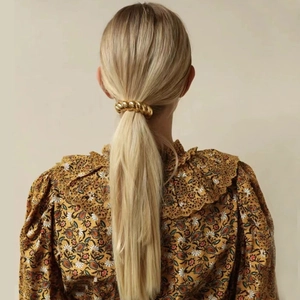Detail of a vintage golden twist metal hair ring securing a ponytail on a model