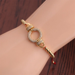 Detail view of red braided cord bracelet with gold ring and pavé-set zirconias