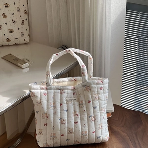 Quilted white cotton tote bag featuring cute cartoon patterns on a wooden stool