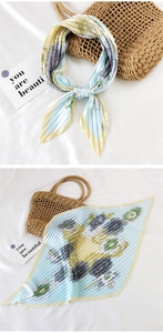 Detail of pleated silk scarf with floral pattern and light blue striped texture