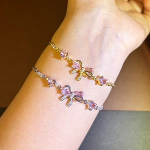 Bowknot heart bracelet with pink zircon in gold and silver finish on hand