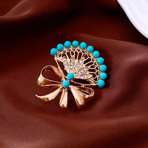 Detail of vintage gold fan brooch with turquoise beads and crystal rhinestones on silk