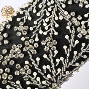 Close-up of black satin evening bag featuring detailed white pearl and diamond floral beading