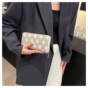 Detail of a beige woven pattern long wallet with gold zipper held by a model