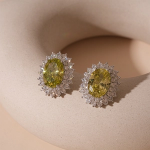 Detailed view of oval yellow zircon stud earrings with silver base and cluster setting