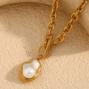 Macro shot of gold-plated thick chain necklace with Baroque pearl and OT toggle clasp