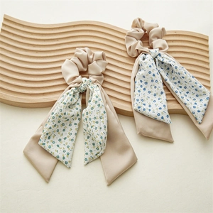 Elegant floral ponytail hair scrunchies with long ribbons on a wooden tray
