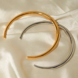 Minimalist 18k gold and silver stainless steel torque collars on beige silk background
