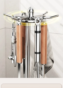 Close-up of a rotating metal utensil holder with wooden handled tools on a white background