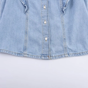Detailopname van lichtblauwe denim stof met witte metalen knopen en fijn stiksel